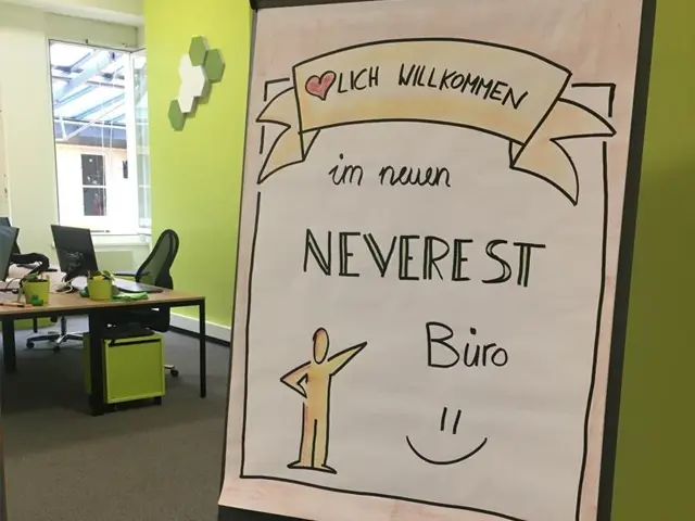 NEVEREST - Standort Krems - Flipchart mit Text "Herzlich Willkomme im neuen NEVEREST Büro" im Hintergrund ist das Büro zu sehen