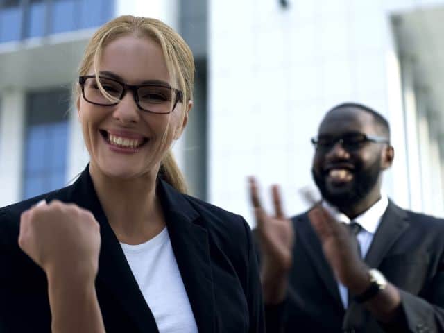 Persönlichkeitsentwicklung Frau Siegerpose Mann klatscht im Hintergrund