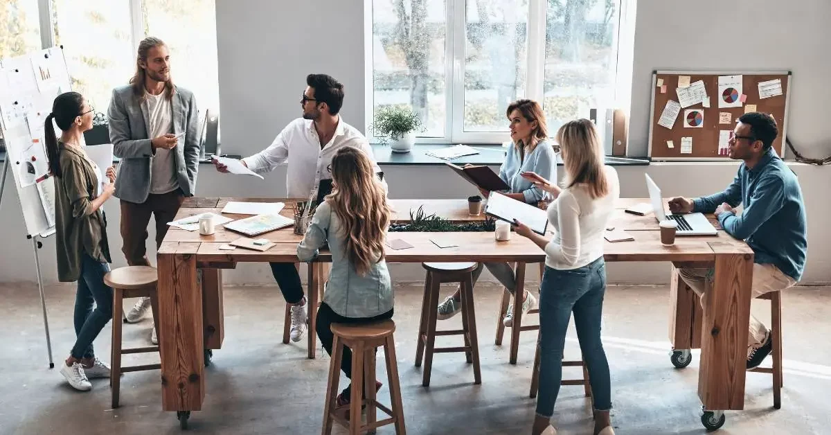 NEVERST Brainstorming großes Team arbeitet mit Moderatorin an Ideen und sitzt dabei an einem Tisch