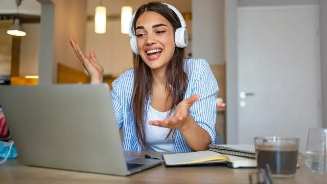 NEVEREST eeducation Frau sitzt mit Kopfhörern vor Laptop und redet