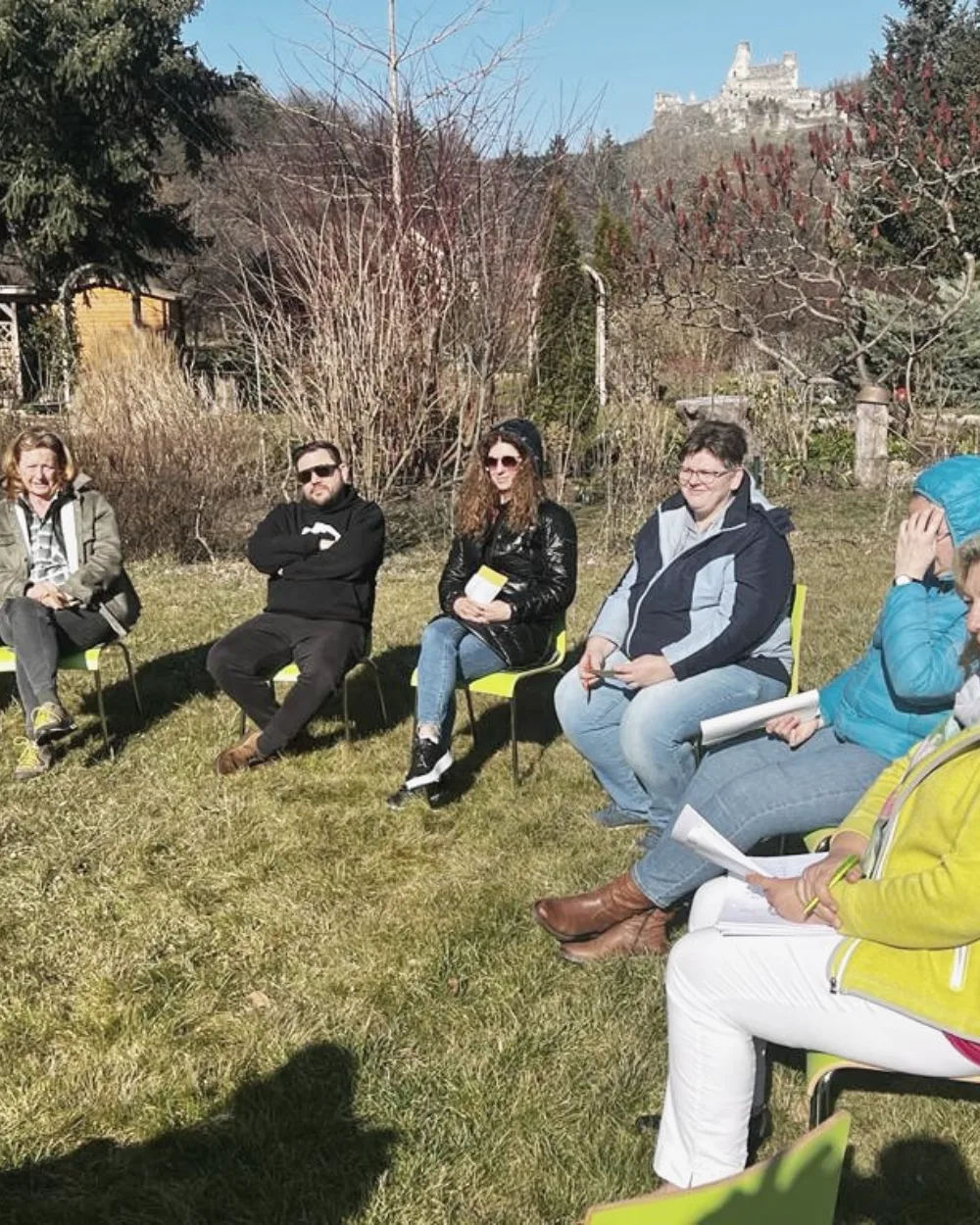 Lehrgangsgruppe sitzt im Kreis in einem Garten